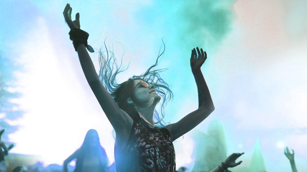 a girl in a crowded concert putting her hands up