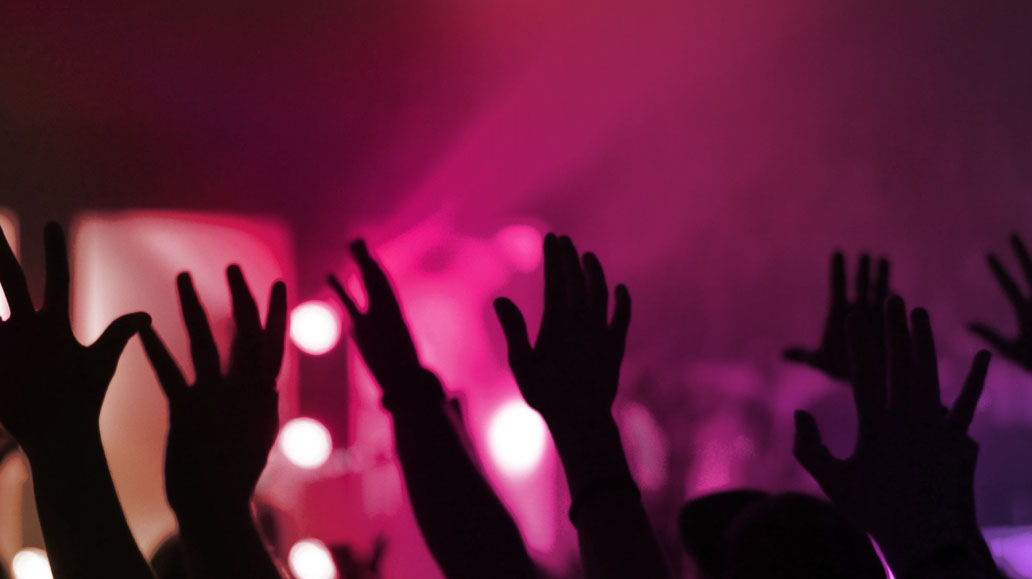 a large group of audiences putting their hands up in a concert
