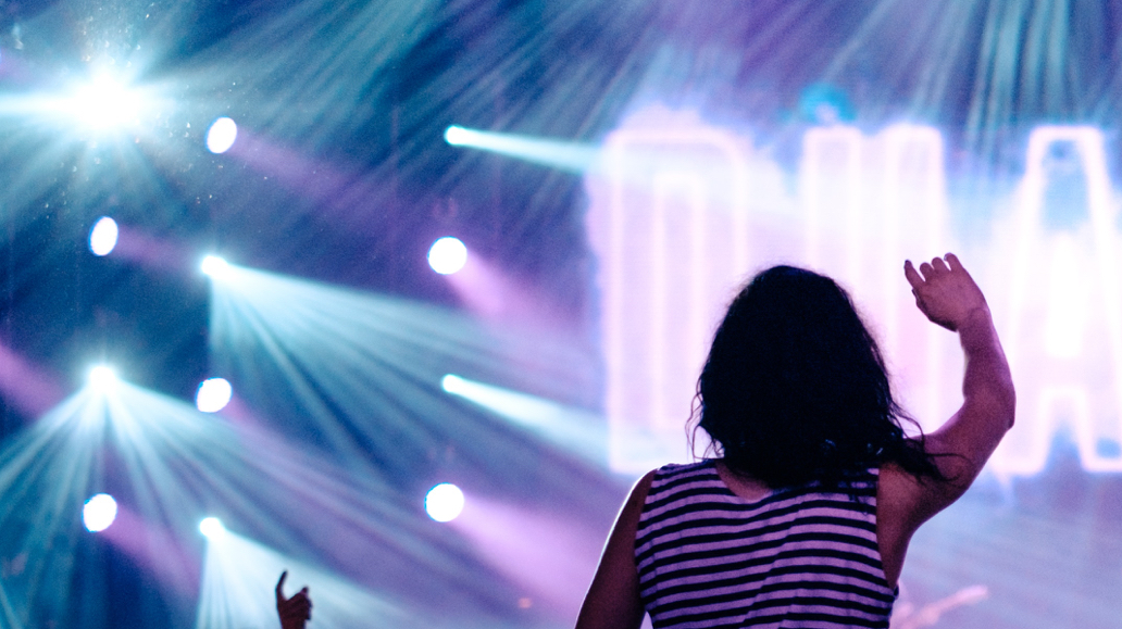 a girl in a concert siting on someone's shoulders and enjoying the concert